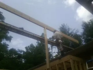 Carpenter setting a ridge beam over a new addition frame — Ice Dam Removal by Roofing Brothers in Ira