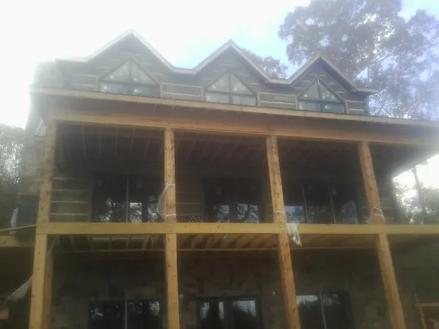 Dormers and porch framing on a large log home under construction — Roof Coating work by our crew in Ira