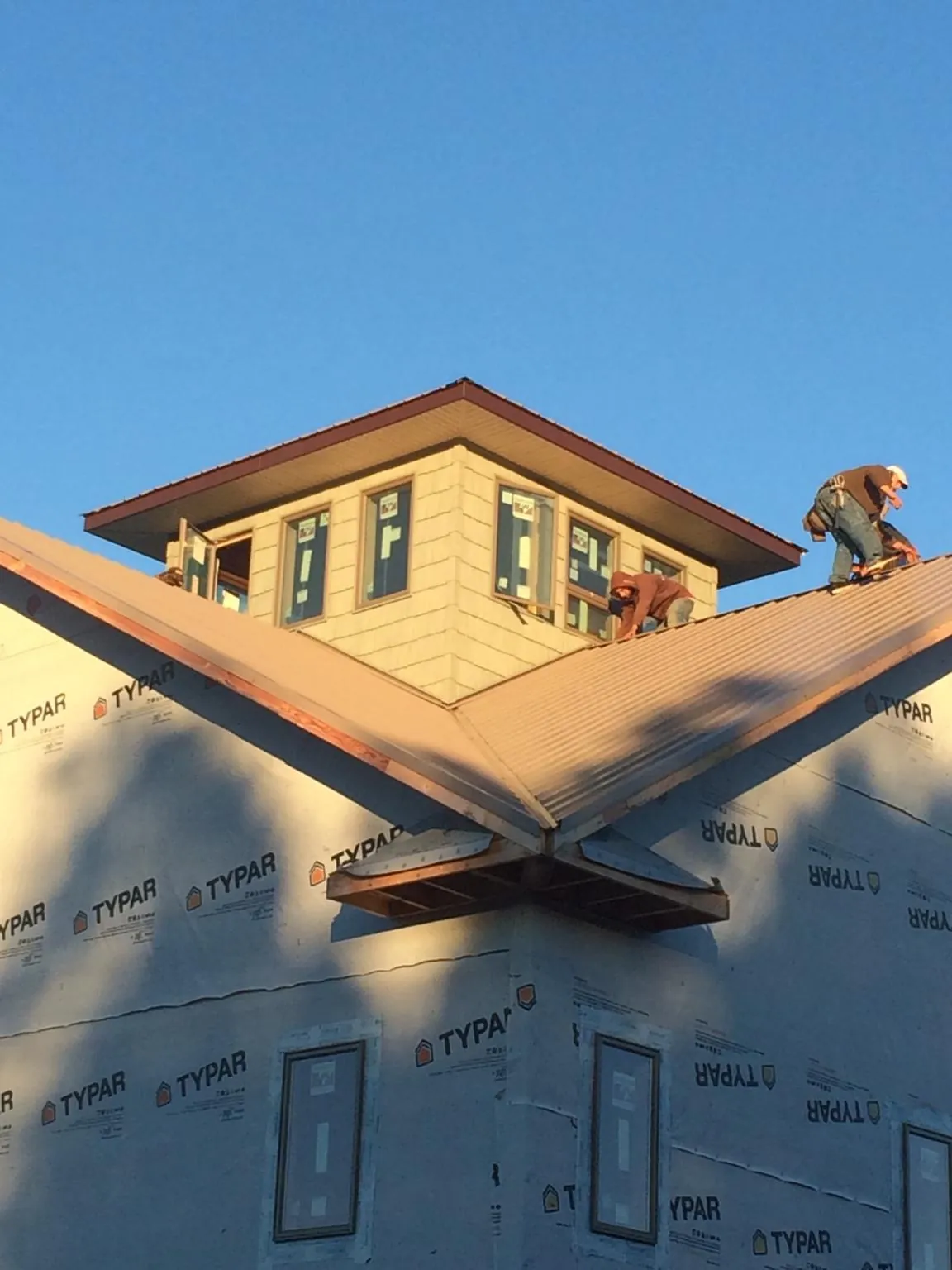 Roofers working around a rooftop cupola on a new metal roof at sunset — Roof Waterproofing in Ira by Roofing Brothers
